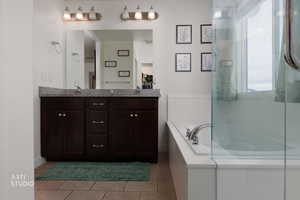 Bathroom featuring double vanity, light tile patterned floors, an enclosed shower, and a bath