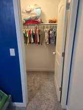 Walk in closet featuring light colored carpet