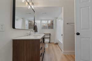 Full bathroom featuring vanity, shower / bathtub combination with curtain, and light wood-style flooring