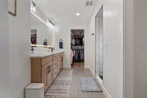 Full bathroom with a walk in closet, double vanity, light tile patterned floors, and recessed lighting