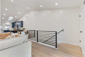 Staircase featuring recessed lighting, wood finished floors, a skylight, and a high ceiling