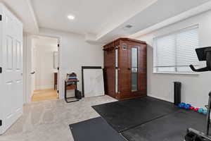 Exercise room with light carpet and baseboards