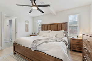 Bedroom featuring beam ceiling, a ceiling fan, light wood-style flooring, and ensuite bathroom