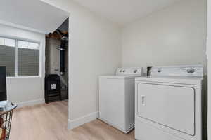 Laundry area featuring light wood finished floors and separate washer and dryer