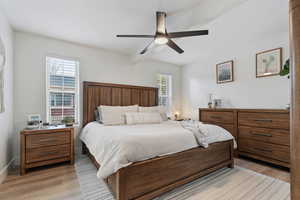 Bedroom with ceiling fan, light wood-style flooring, and beam ceiling