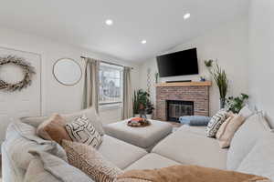 Living area featuring lofted ceiling, a brick fireplace, and recessed lighting