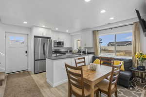 Kitchen with dark stone countertops, stainless steel appliances, white cabinets, a peninsula, and recessed lighting