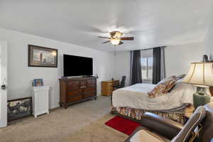 Carpeted bedroom with a ceiling fan and a textured ceiling
