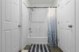 Full bathroom featuring shower / bath combo and dark wood-style flooring