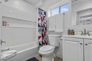 Bathroom with vanity, shower / bath combination with curtain, and light wood-type flooring