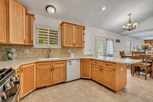 Kitchen with a peninsula, gas stove, dishwasher, backsplash, and light wood finish cabinetry