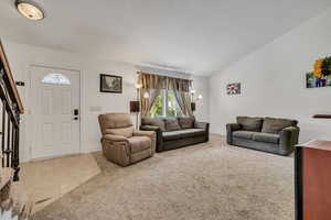 Living area featuring light colored carpet, light tile patterned floors, and lofted ceiling