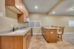 Kitchen with a peninsula, a breakfast bar, light stone countertops, recessed lighting, and wood finish cabinets
