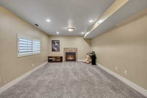 Unfurnished living room with carpet flooring, a fireplace, and recessed lighting