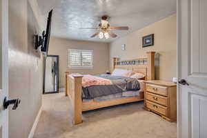 Bedroom featuring light carpet, a ceiling fan, and a textured ceiling