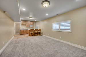 Kitchen featuring light countertops, light carpet, recessed lighting, white microwave, and open floor plan