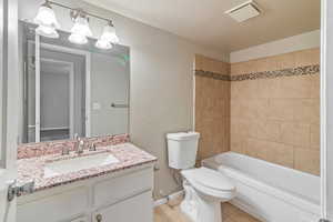 Bathroom with vanity, a textured wall, shower / tub combination, and light tile patterned flooring