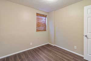Empty room featuring dark wood-type flooring and a textured ceiling