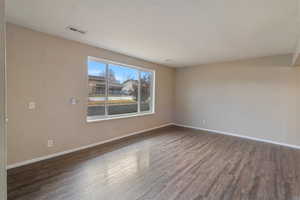 Spare room with dark wood-style floors and baseboards