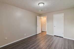 Unfurnished bedroom featuring dark wood-type flooring and a textured ceiling
