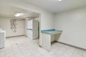 Community laundry with washer and clothes dryer, stacked washing machine and dryer, and light tile patterned floors