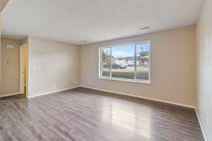 Spare room with wood finished floors and a textured ceiling