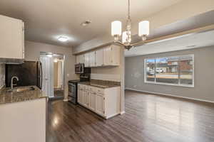 Kitchen featuring dark stone countertops, stainless steel range with electric stovetop, dark wood finished floors, and decorative backsplash