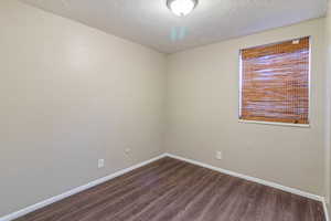 Unfurnished room featuring dark wood-type flooring and a textured ceiling