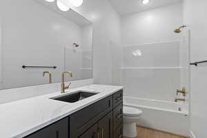 Bathroom with vanity, washtub / shower combination, and light wood-style flooring