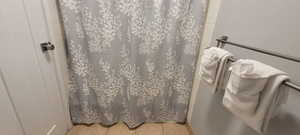 Bathroom with curtained shower and light tile patterned floors