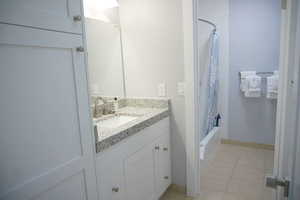 Full bathroom with shower / bath combo, vanity, and light tile patterned floors