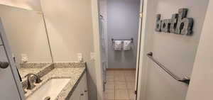 Full bathroom with curtained shower, vanity, and light tile patterned floors