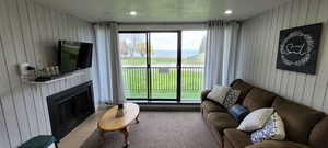 Carpeted living area with wooden walls, a fireplace, and a textured ceiling
