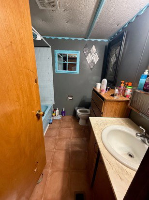 Full bath featuring vanity, shower / tub combination, light tile patterned flooring, and a textured ceiling