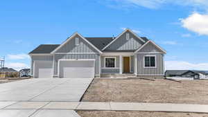 View of front of home with covered porch, roof with shingles, concrete driveway, and an attached garage