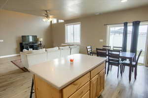 Kitchen with light wood finish cabinets, light wood finished floors, a center island, and light countertops