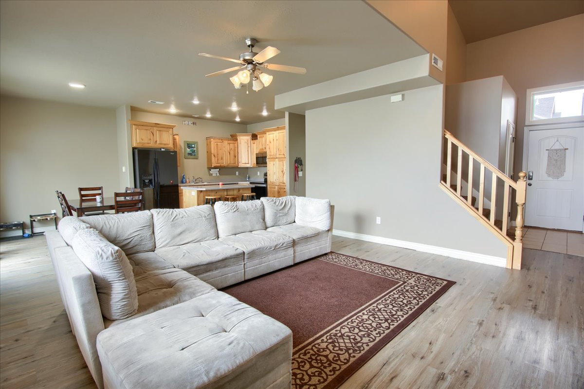 Living room with ceiling fan, light wood-style flooring, and recessed lighting