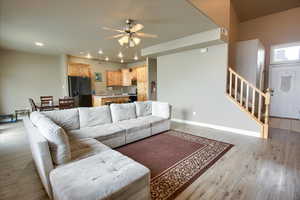 Living room with ceiling fan, light wood-style flooring, and recessed lighting