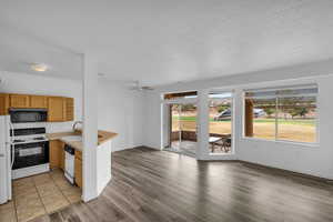 Kitchen featuring white appliances, light countertops, a peninsula, open floor plan, and a textured ceiling