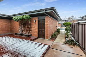 Doorway to property featuring brick siding and a gate