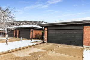 View of front facade with brick siding, driveway, a garage, a mountain view, and an outdoor structure