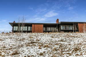 View of front of home featuring a chimney, brick siding, and a balcony