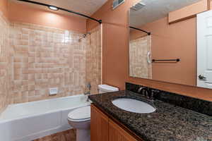 Bathroom featuring shower / washtub combination, a textured ceiling, vanity, and dark wood-type flooring