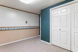 Unfurnished bedroom with crown molding, a closet, carpet, and a textured ceiling