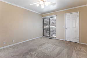 Unfurnished room featuring a ceiling fan, ornamental molding, and carpet