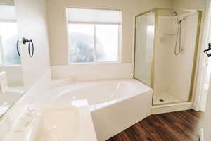Bathroom featuring a stall shower, a bath, dark wood finished floors, and vanity