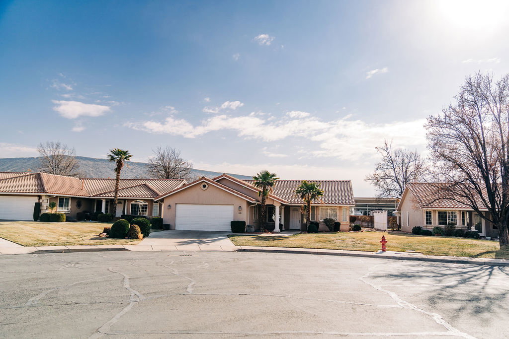 View of front facade with a tile roof, concrete driveway, a residential view, and stucco siding