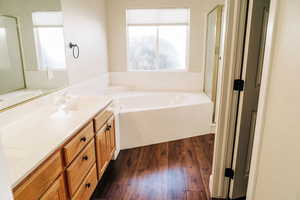 Bathroom with healthy amount of natural light, a bath, double vanity, and a stall shower