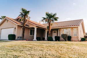 View of front of property featuring stucco siding, a front yard, a garage, and a tile roof