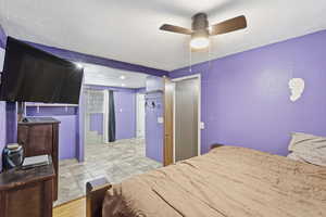 Bedroom with a ceiling fan and a textured ceiling